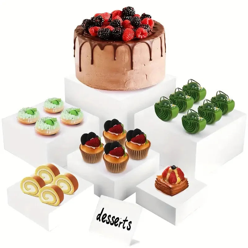 Six white geometric cube dessert display stands arranged on a table.