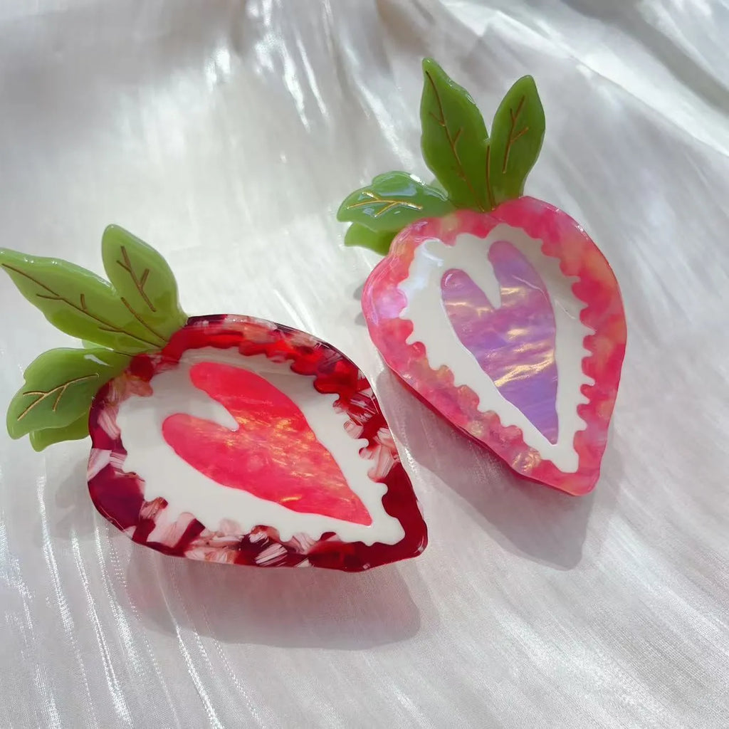 Red and pink strawberry-shaped metal charm hair clip for girls on a white background.