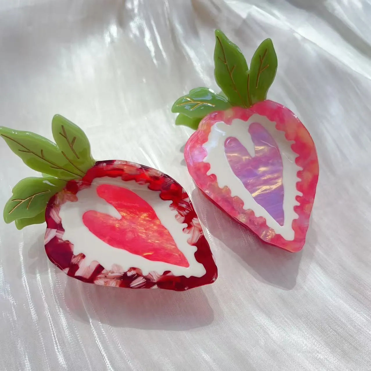 Red and pink strawberry-shaped metal charm hair clip for girls on a white background.