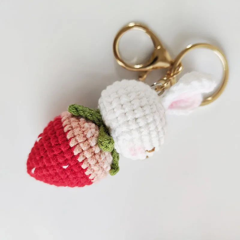 White hand-woven wire pendant with a cartoon rabbit and strawberry design, shown with its attachment key.