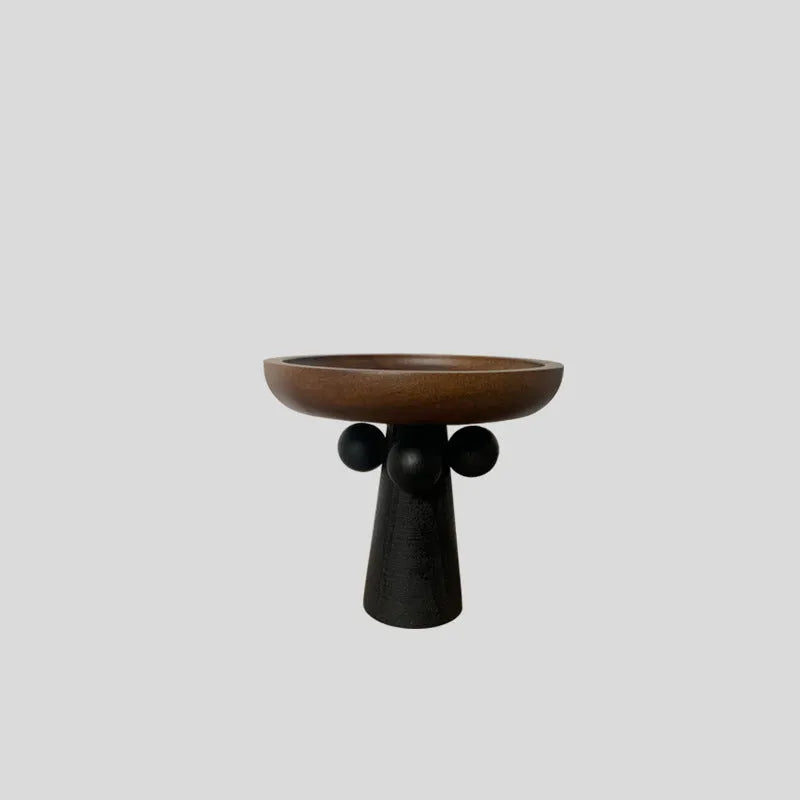 Round high-legged wooden tray in modern style holding a candle and perfume bottle for home decor.
