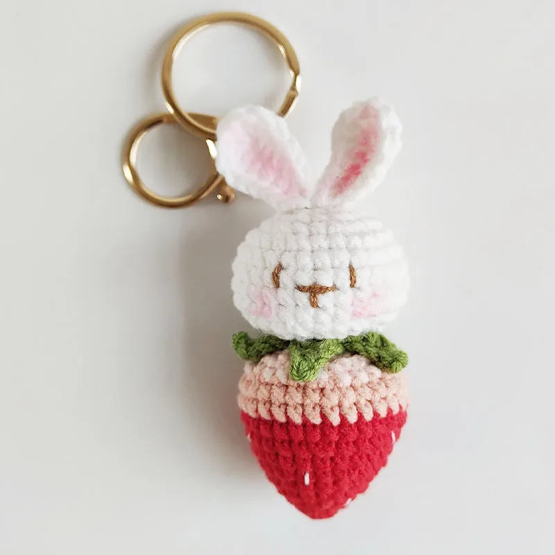 White hand-woven wire pendant with a cartoon rabbit and strawberry design, shown with its attachment key.
