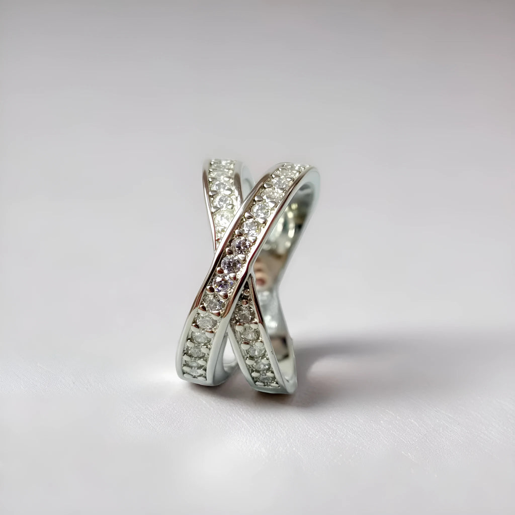 A silver or rose gold metal ring featuring a heart-shaped cross centrepiece with micro-inlaid zircon details.