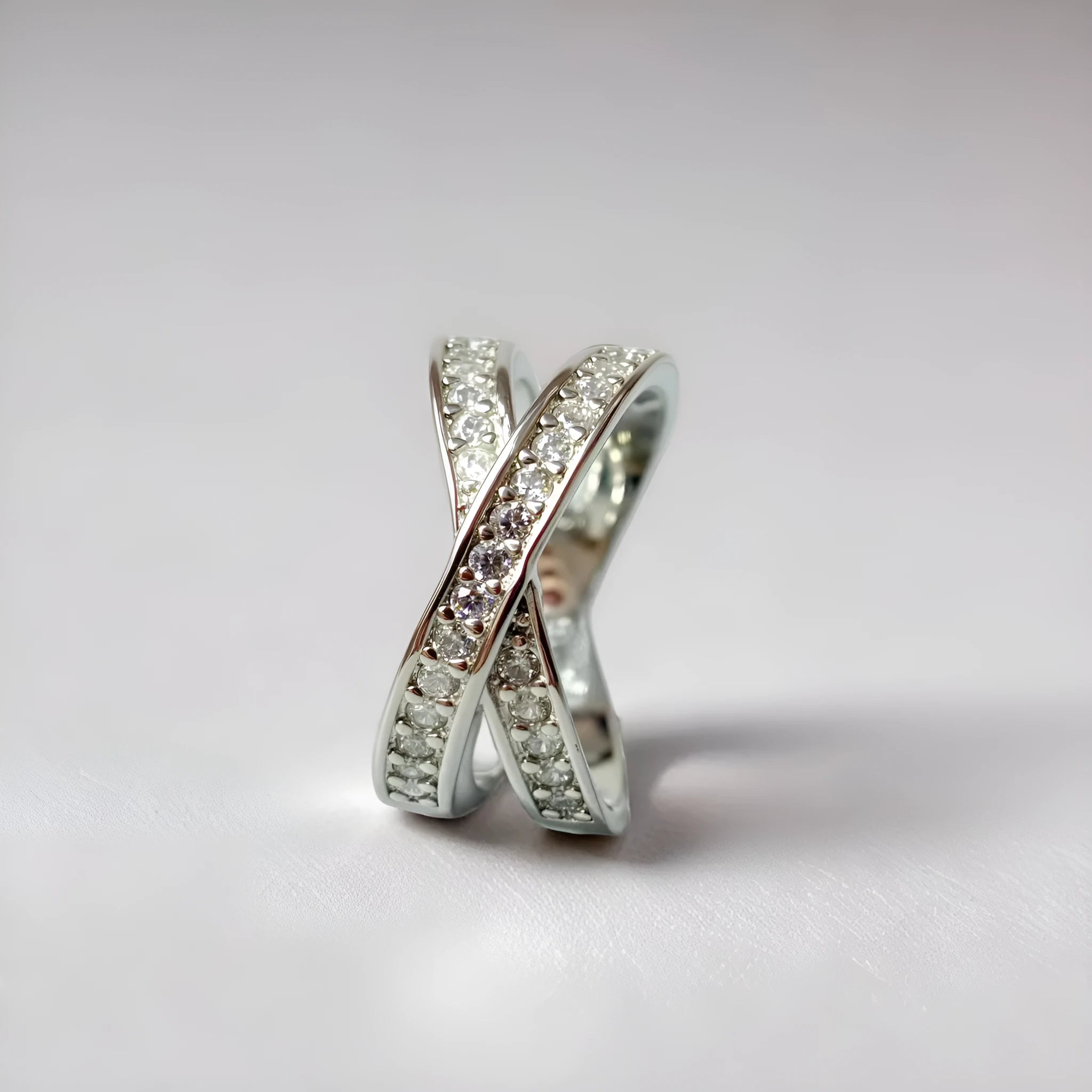 A silver or rose gold metal ring featuring a heart-shaped cross centrepiece with micro-inlaid zircon details.