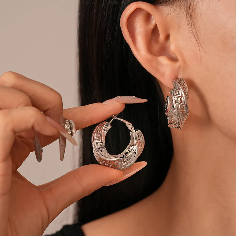 A pair of twisted round geometric hollow stud earrings for women in a gold or silver metallic finish.