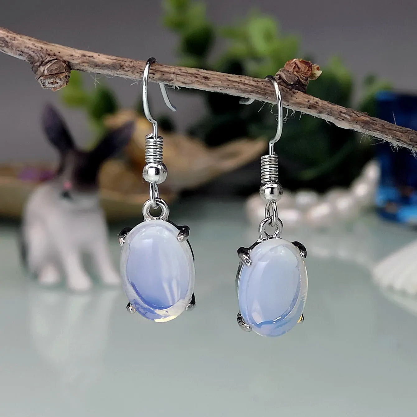 A pair of white opal-coloured drop earrings with a retro cross design on an alloy pendant.