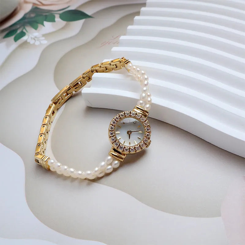 Light gold women's bracelet watch with freshwater pearls and an 18mm round dial on a stainless steel strap.