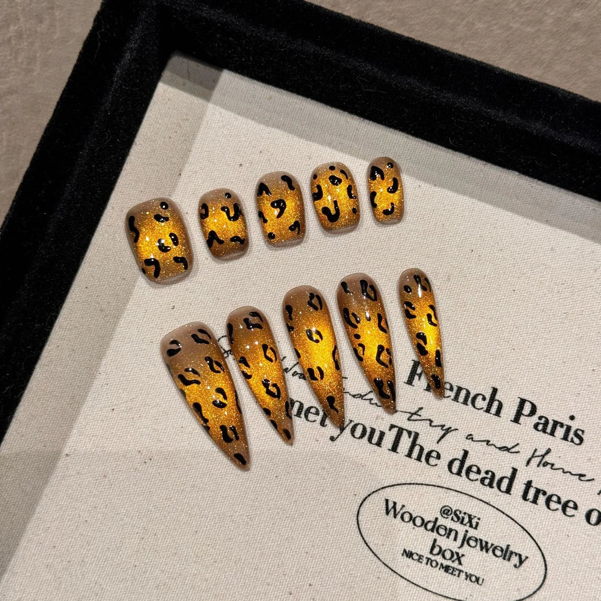 Handmade false nails with tiger pattern, leopard print and white base in a cat eye shape.