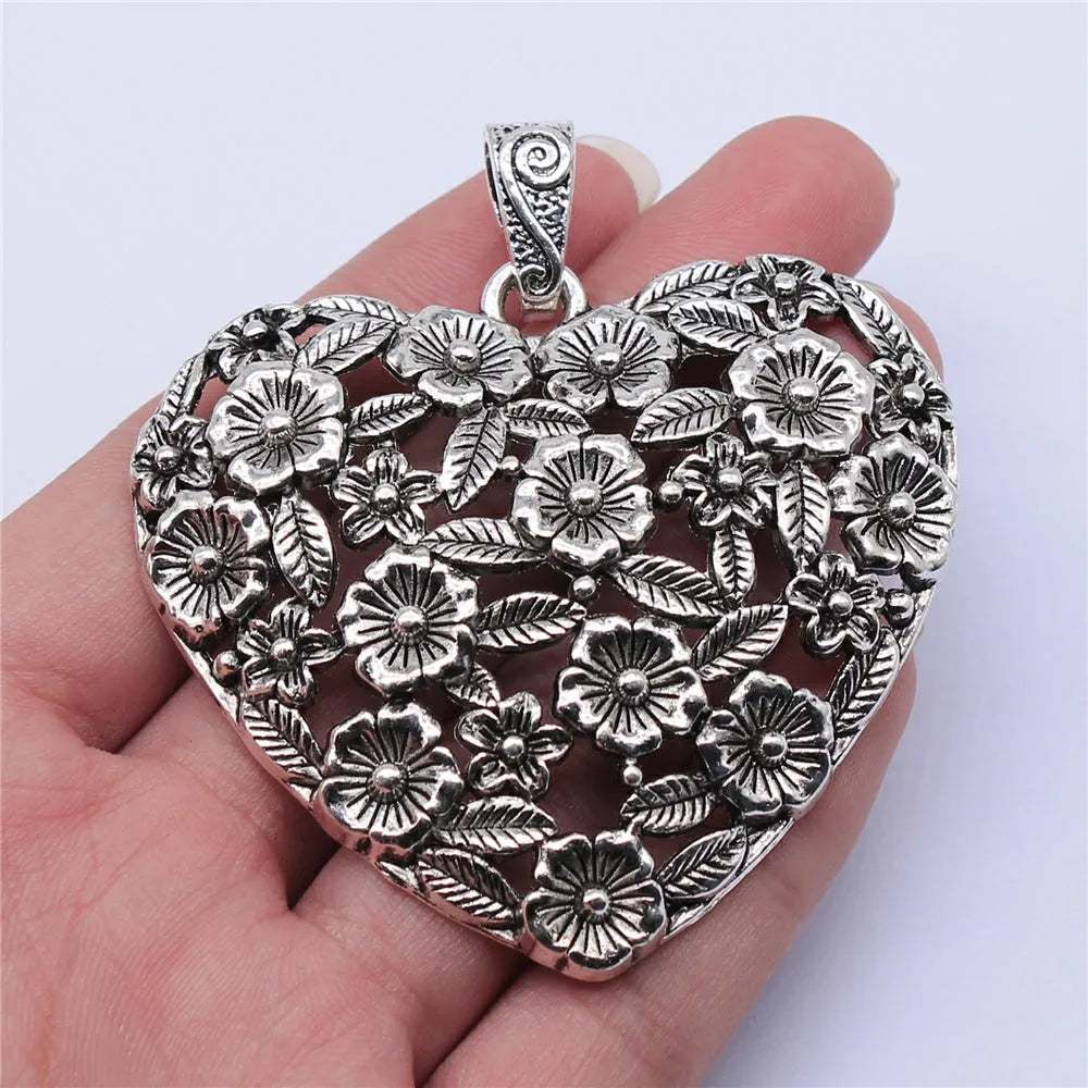 Ancient silver hollow flower love symbol alloy pendant on a dark background.