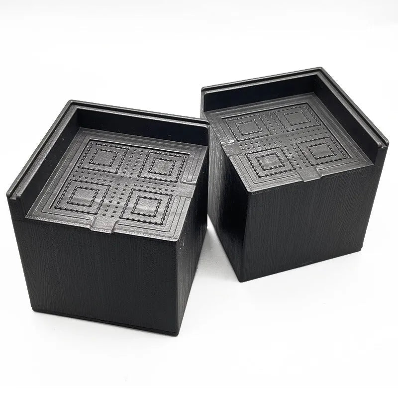Four black plastic furniture foot mats for height adjustment and floor protection