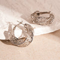 A pair of twisted round geometric hollow stud earrings for women in a gold or silver metallic finish.