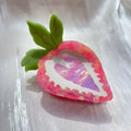 Red and pink strawberry-shaped metal charm hair clip for girls on a white background.