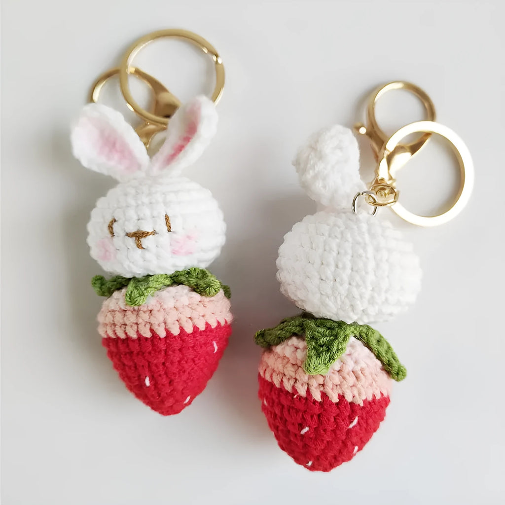 White hand-woven wire pendant with a cartoon rabbit and strawberry design, shown with its attachment key.