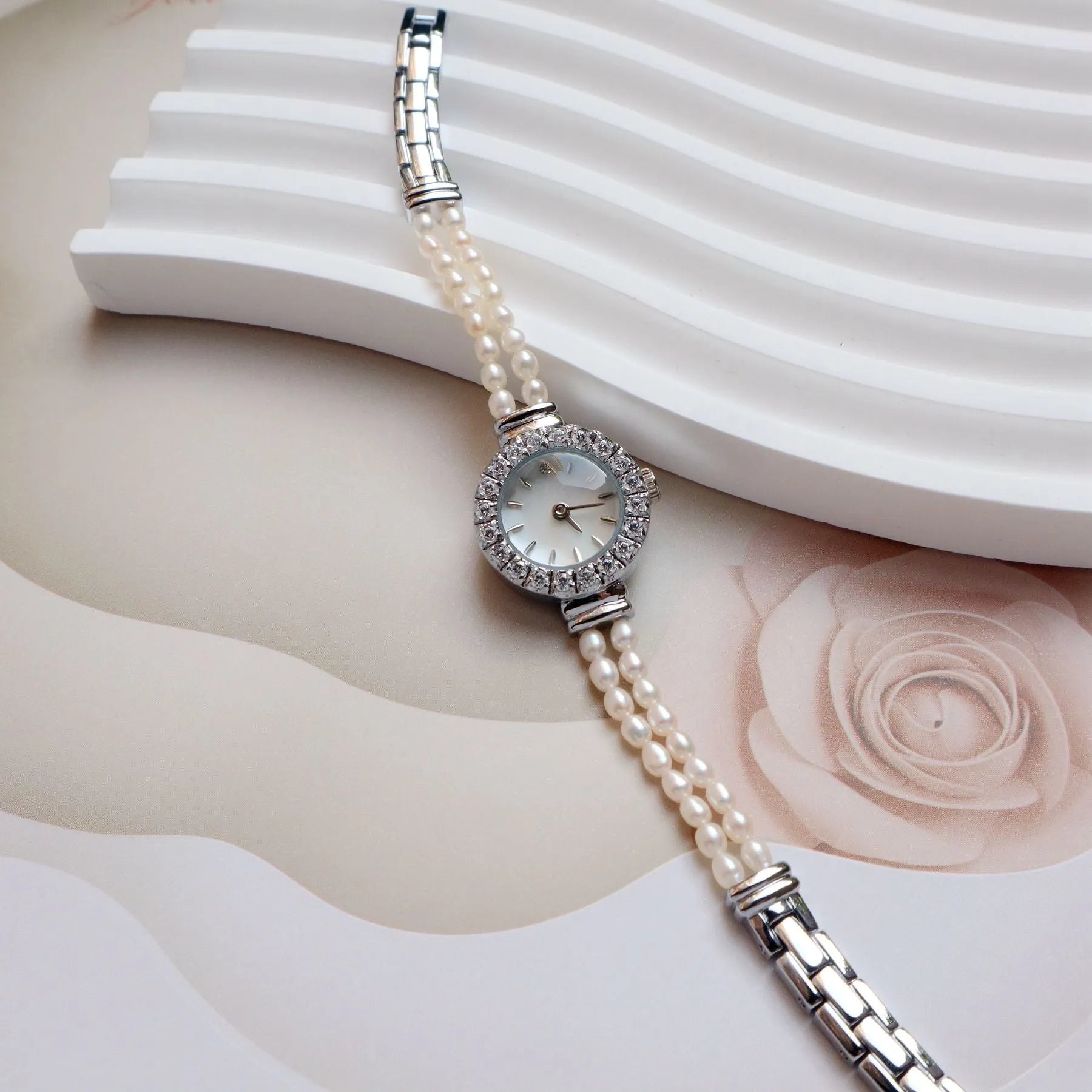 Light gold women's bracelet watch with freshwater pearls and an 18mm round dial on a stainless steel strap.