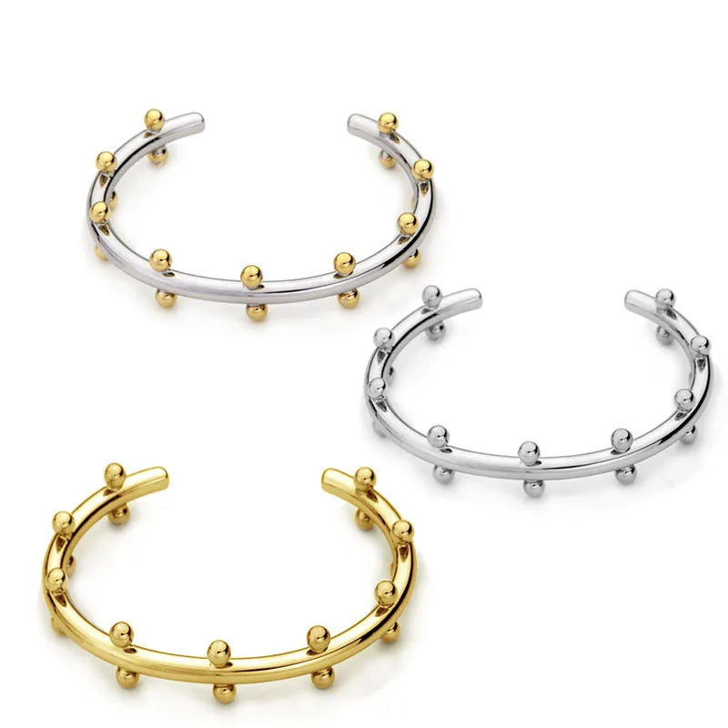 Stainless steel C-shaped bracelet with textured bean beads and rivet details in gold, steel colour, or steel colour gold finishes