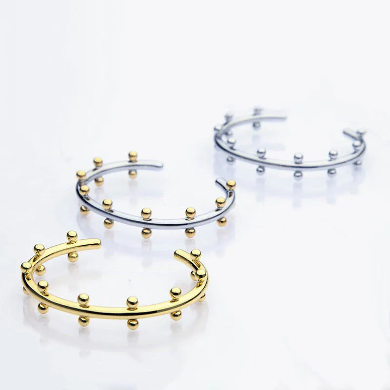 Stainless steel C-shaped bracelet with textured bean beads and rivet details in gold, steel colour, or steel colour gold finishes