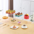 Six white geometric cube dessert display stands arranged on a table.