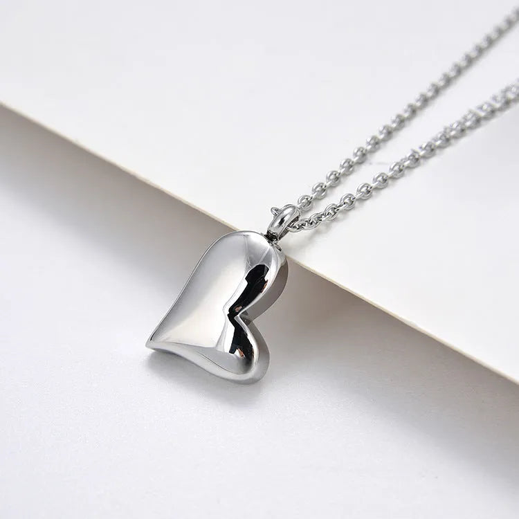 Silver curved peach heart pendant on a stainless steel necklace with an extension chain.