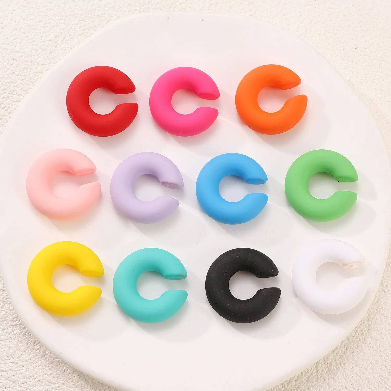 Close-up of a pair of matte coarse round C-shaped clip-on earrings for women in a candy colour.