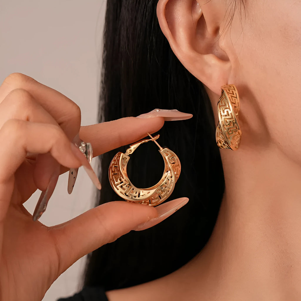 A pair of twisted round geometric hollow stud earrings for women in a gold or silver metallic finish.