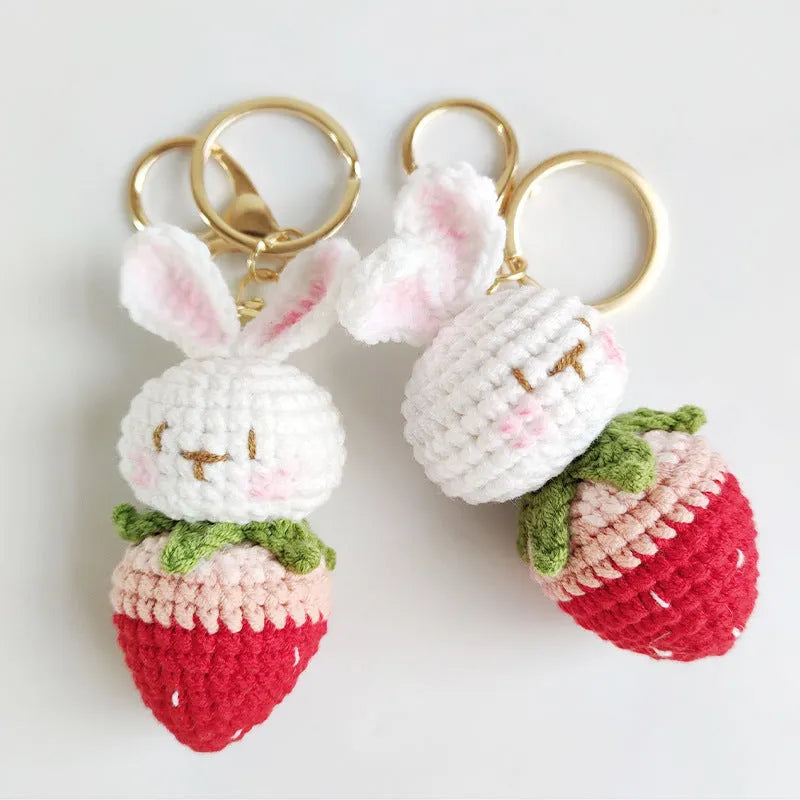 White hand-woven wire pendant with a cartoon rabbit and strawberry design, shown with its attachment key.