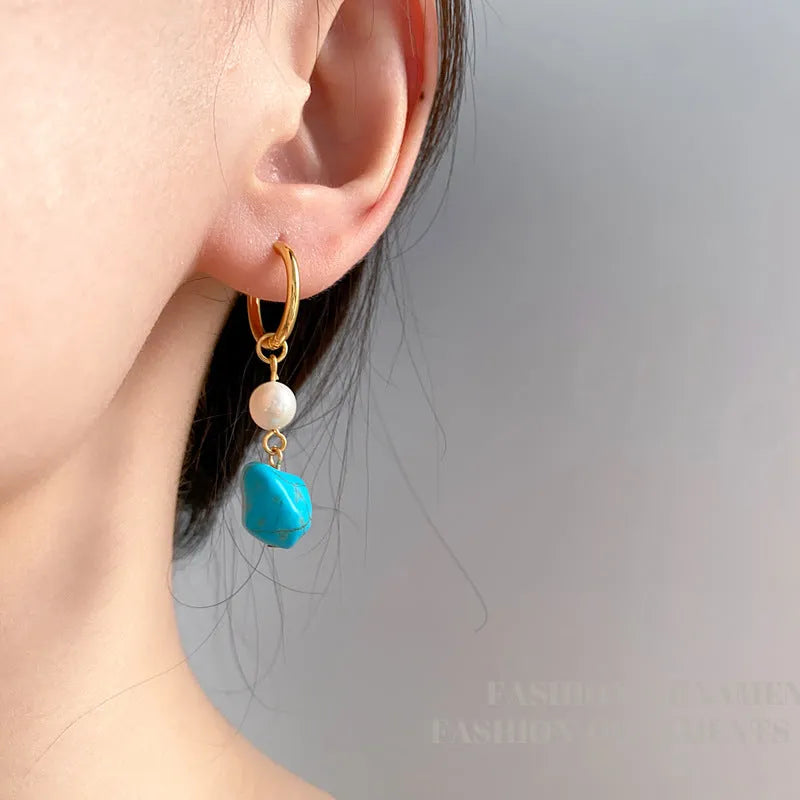 A set of two pairs of women's ear clips: one short and one dangle style, with geometric copper design, turquoise, and cultured pearls.