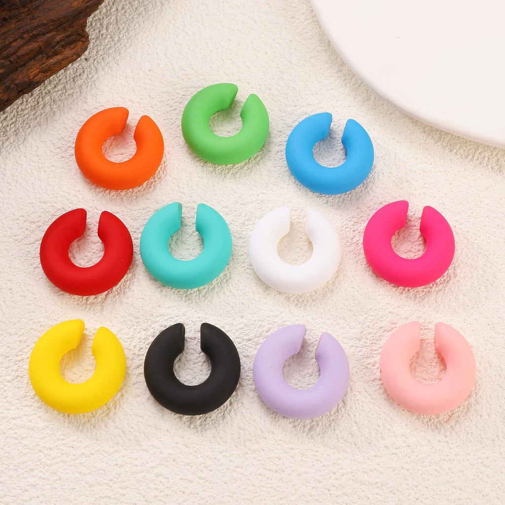 Close-up of a pair of matte coarse round C-shaped clip-on earrings for women in a candy colour.