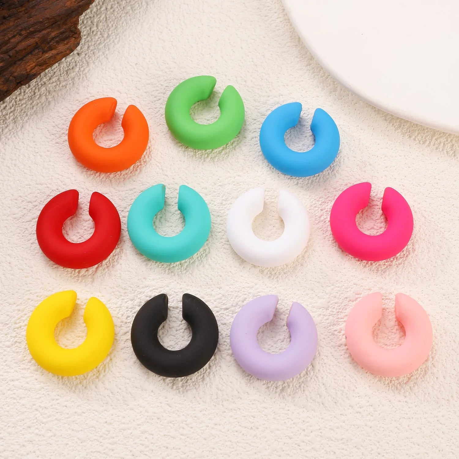 Close-up of a pair of matte coarse round C-shaped clip-on earrings for women in a candy colour.