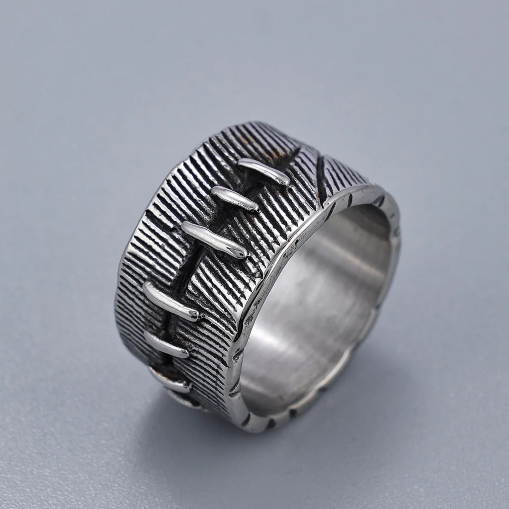 A dark geometric titanium steel ring with punk stitching and a double ring design on a grey background.