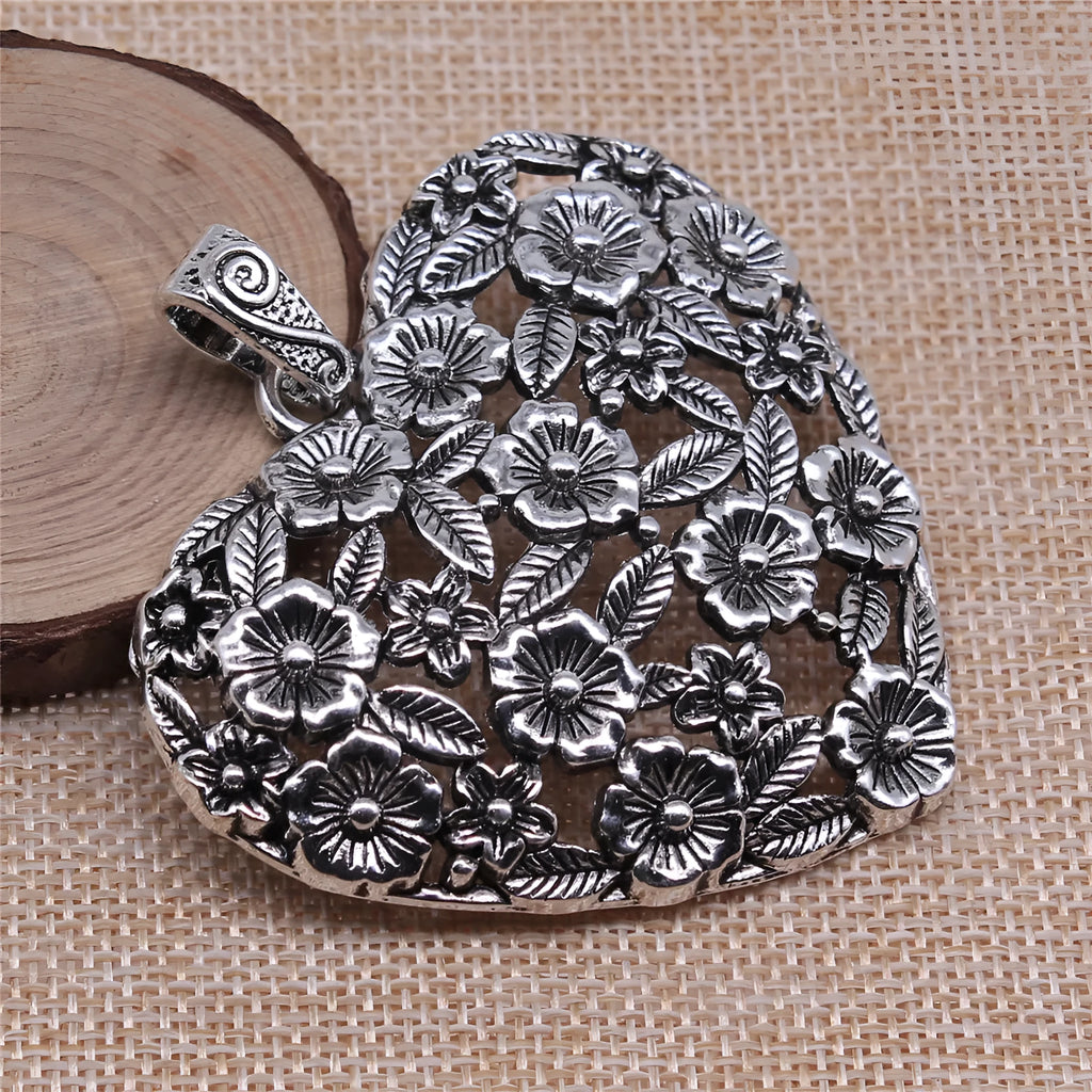 Ancient silver hollow flower love symbol alloy pendant on a dark background.