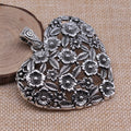 Ancient silver hollow flower love symbol alloy pendant on a dark background.