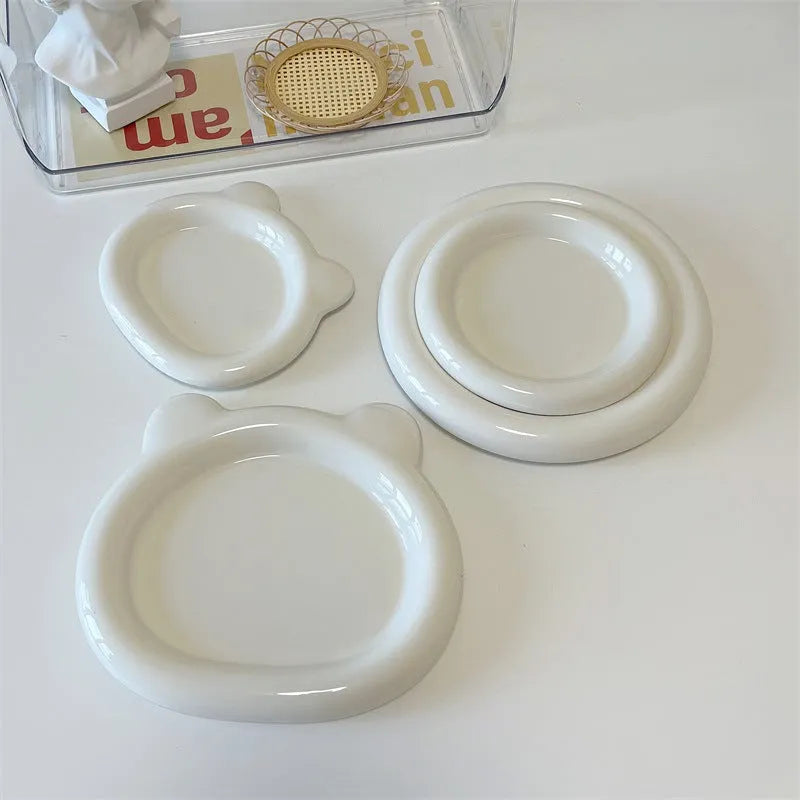 White ceramic plate with cartoon bear doodle design, shown next to round toot design plate, both microwave safe.