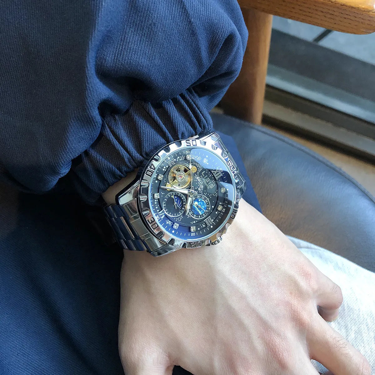 Men's silver automatic mechanical watch with black starry dial on leather strap showing transparent case back
