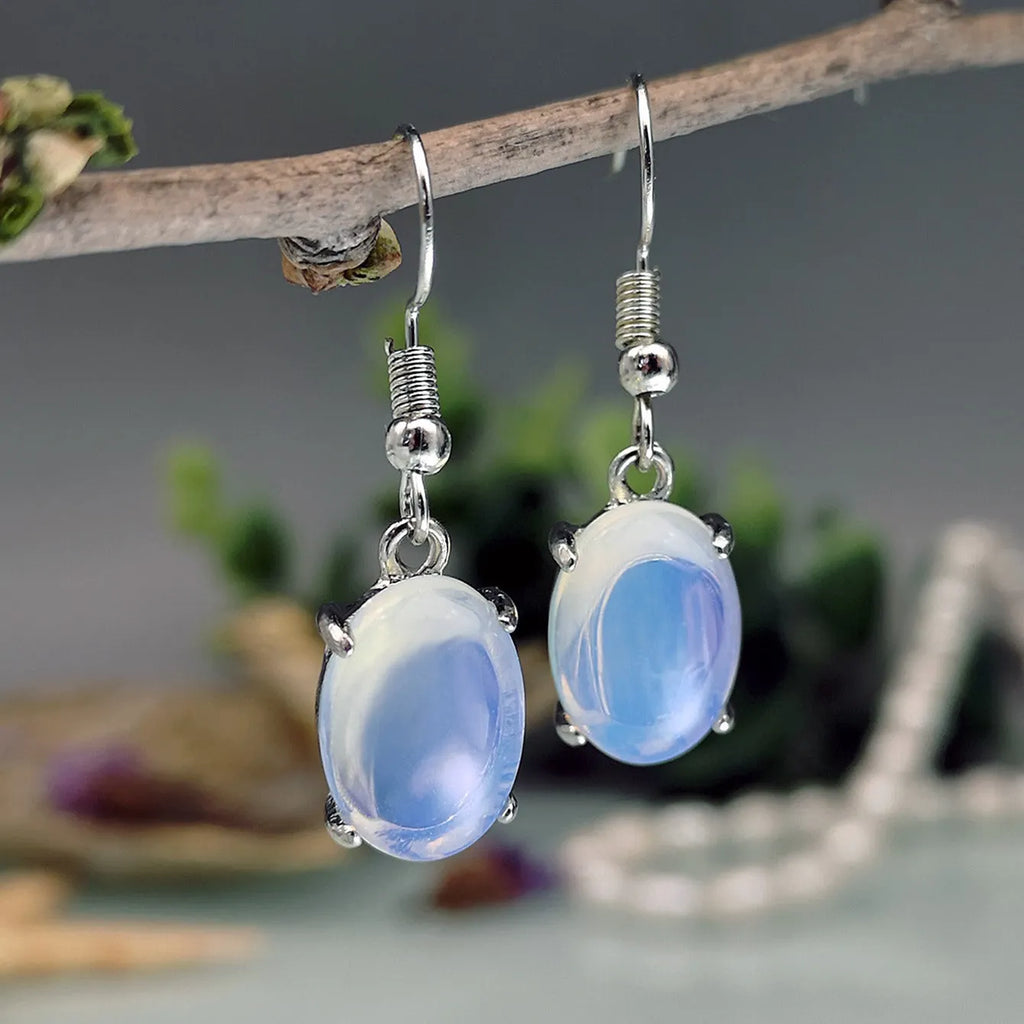 A pair of white opal-coloured drop earrings with a retro cross design on an alloy pendant.