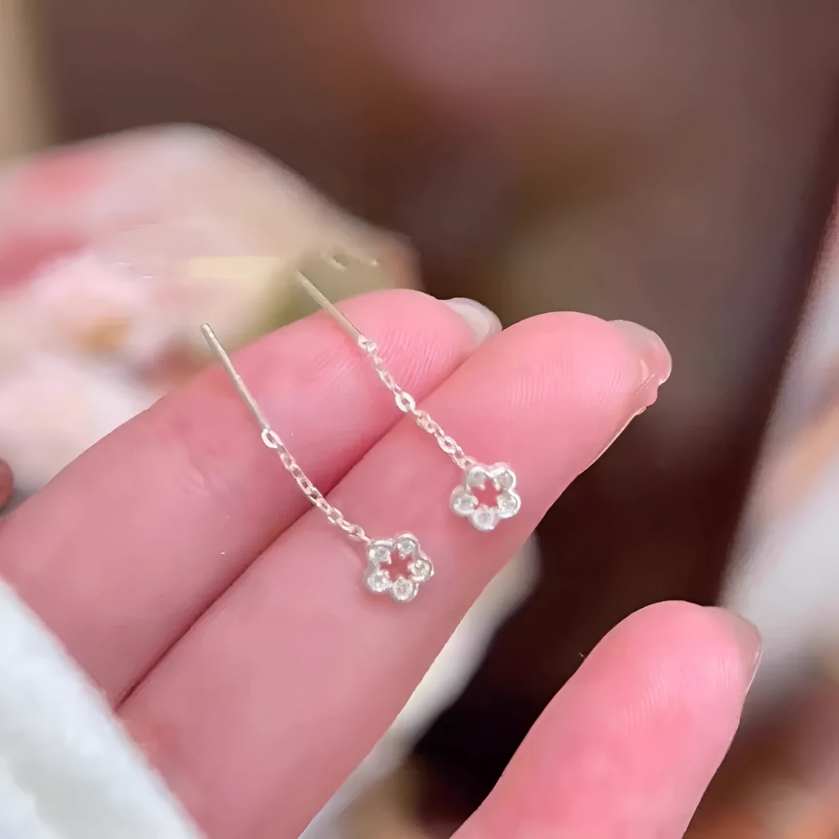 A pair of silver-colour alloy drop earrings featuring a detailed hollow flower design with visible petals.
