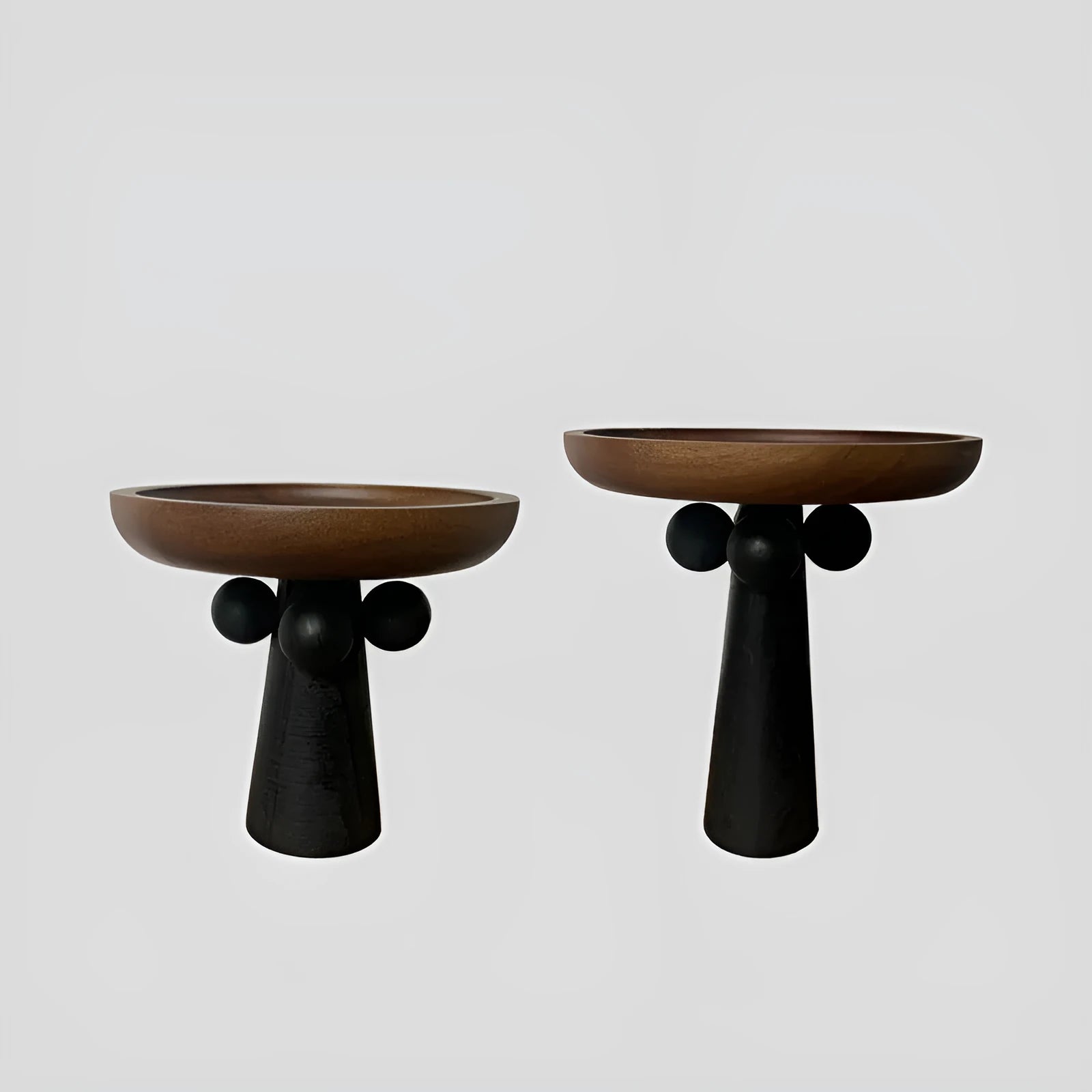 Round high-legged wooden tray in modern style holding a candle and perfume bottle for home decor.