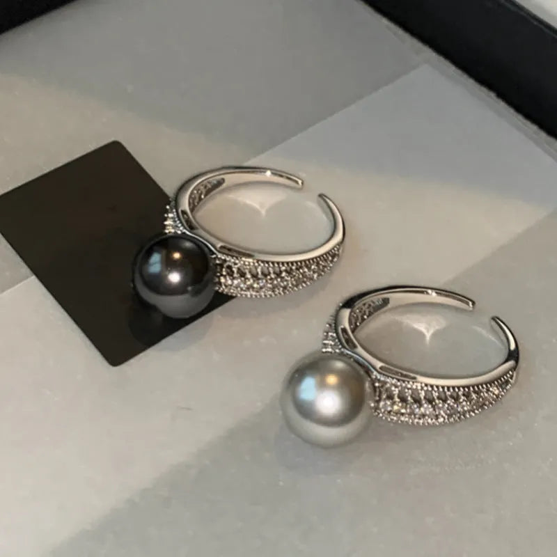 Geometric copper adjustable ring with a black pearl for women, shown on an index finger.