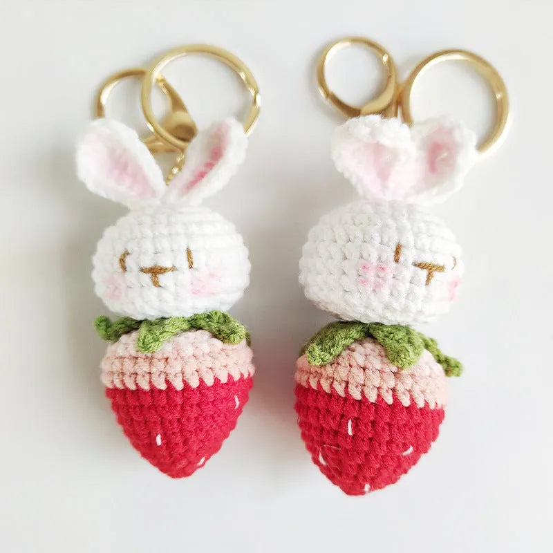 White hand-woven wire pendant with a cartoon rabbit and strawberry design, shown with its attachment key.