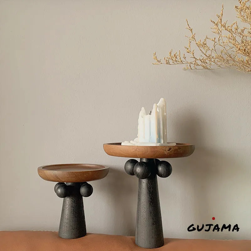Round high-legged wooden tray in modern style holding a candle and perfume bottle for home decor.