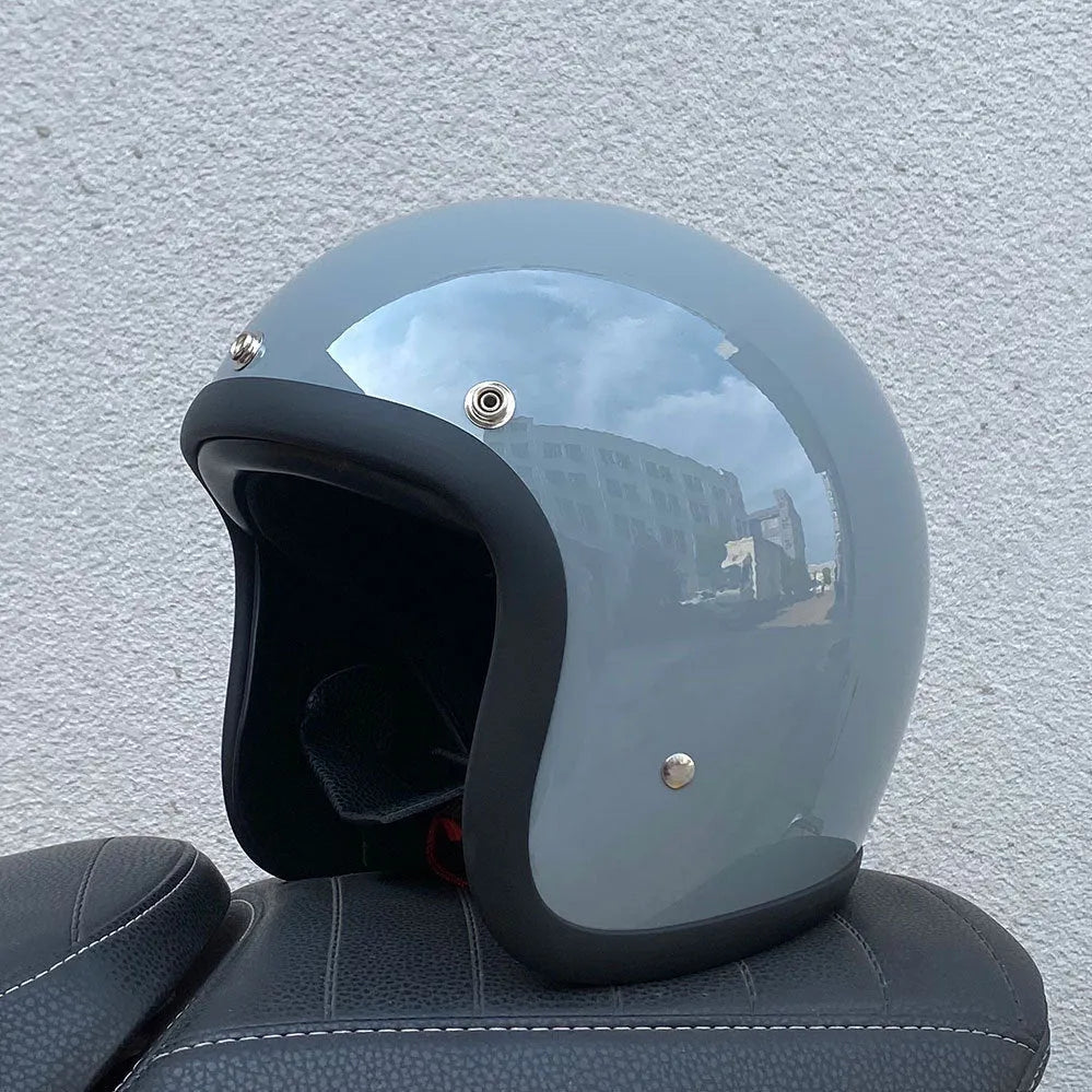 Retro-style open-face motorcycle helmet in fibreglass, shown in a choice of colours including Cement Grey and Matte Black Flower.