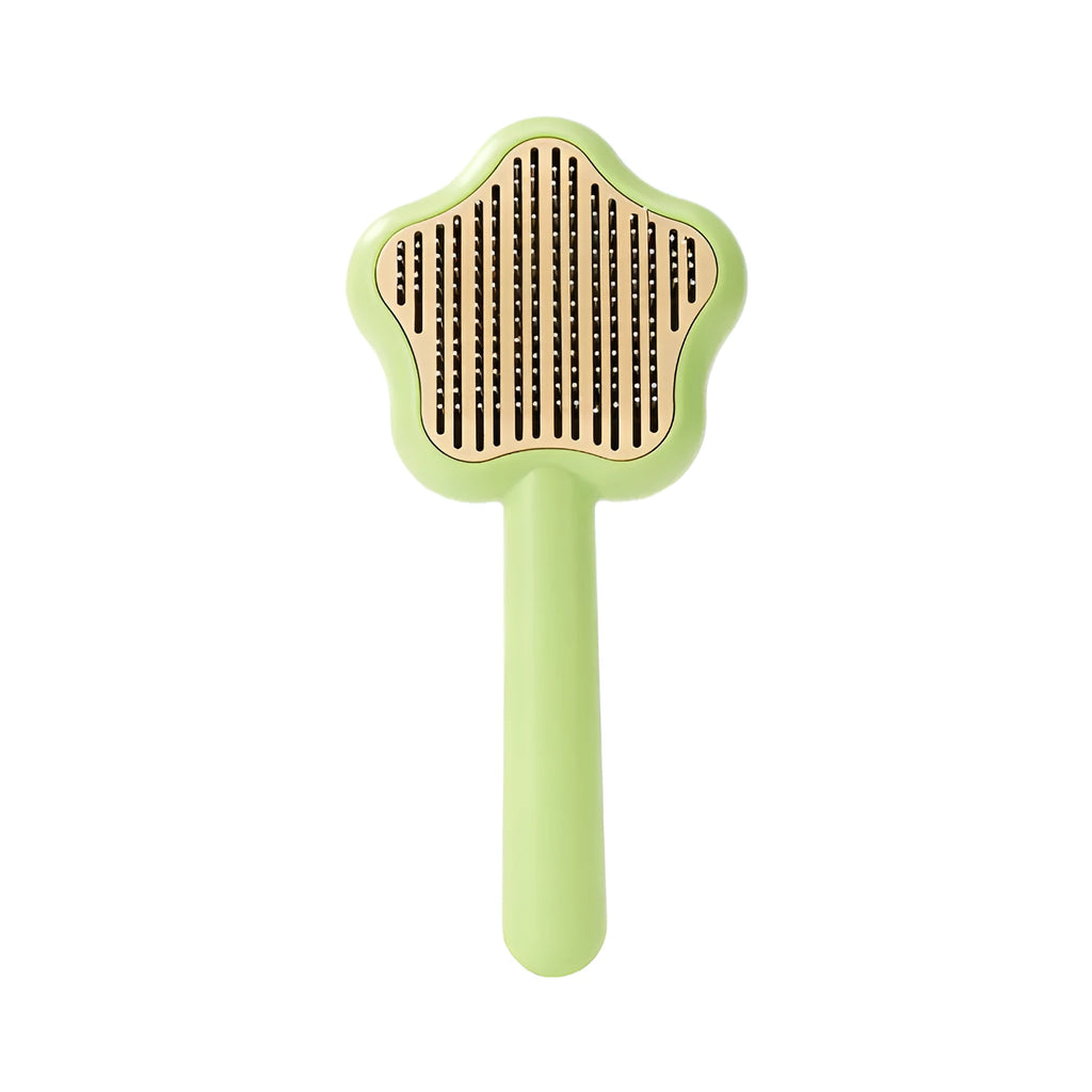 Green self-cleaning pet comb with stainless steel needles on a white background.