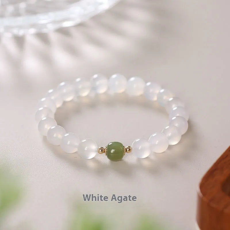 Handmade white agate crystal bracelet with cinnabar details on a wrist, showing 8mm bead size.