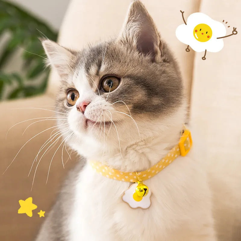 Adjustable green cat collar with a metal bell and a red bow tie pendant fastened around a small dog's neck.