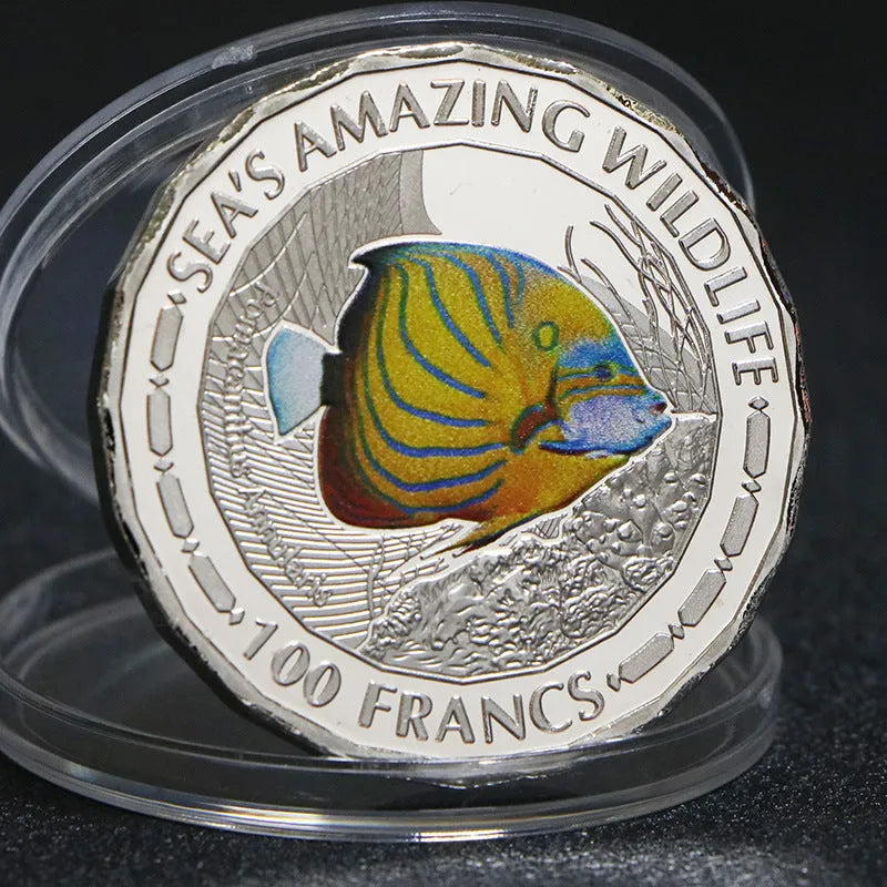 Set of eight silver plated commemorative coins with tropical fish and marine animal designs, 40mm diameter, in acrylic box