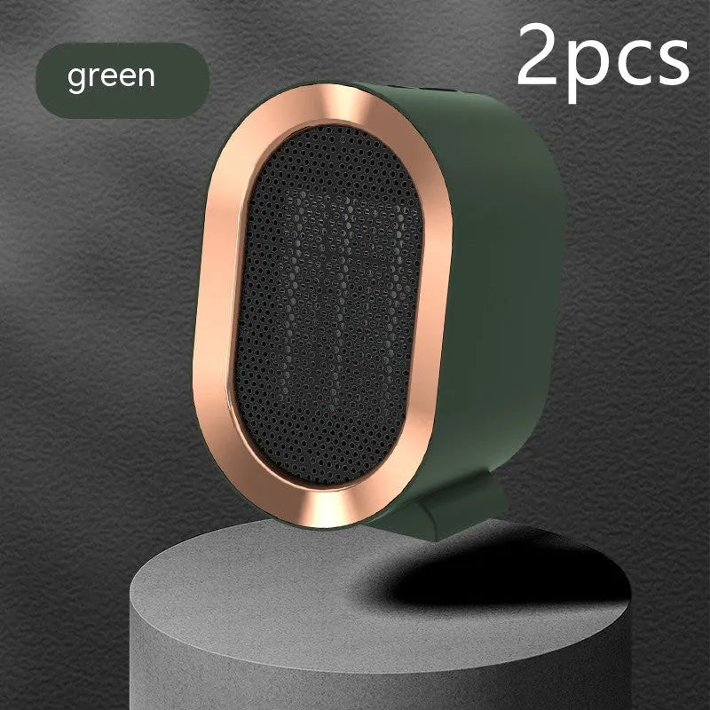 A compact black desktop electric fan heater with mechanical control dials on a wooden desk.
