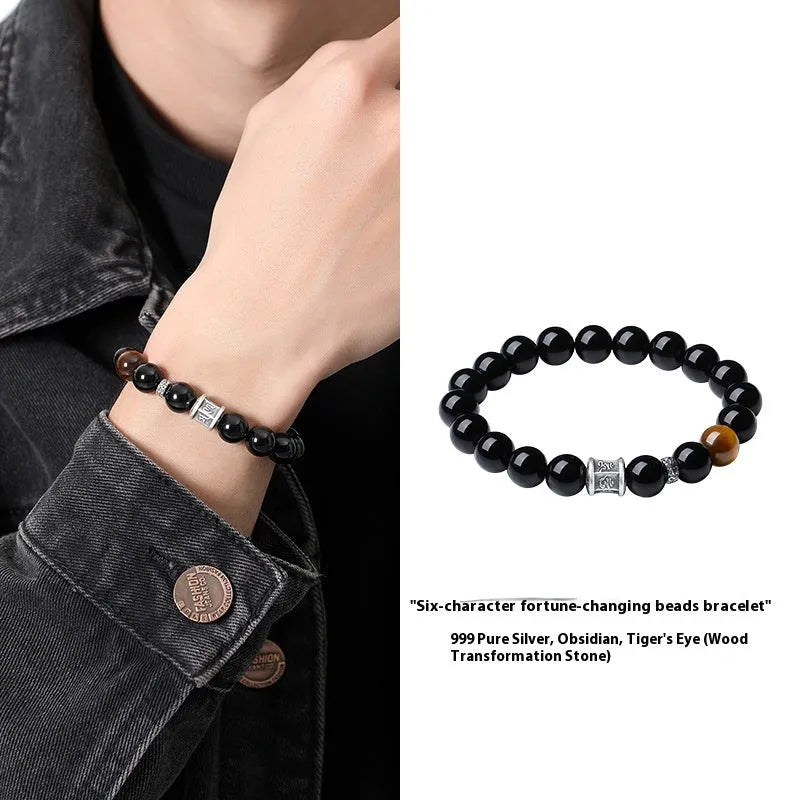 Black obsidian prayer wheel bracelet for men with a hand-woven silver clasp on a wrist.