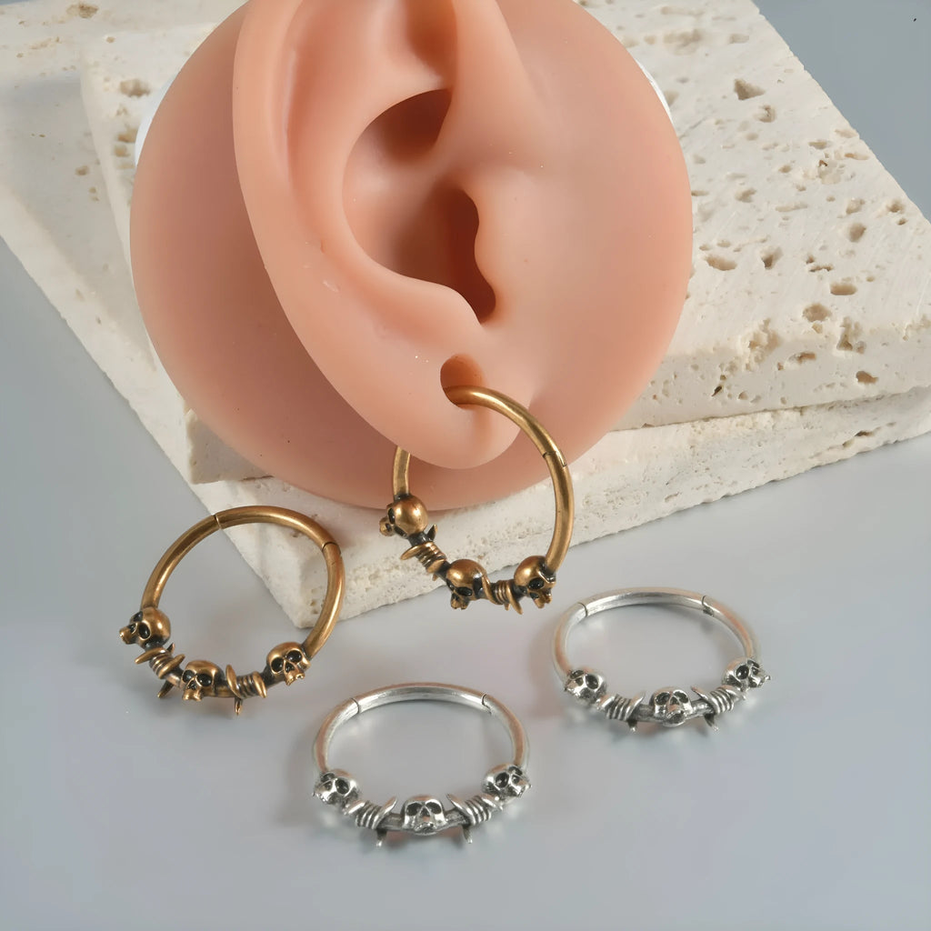 A pair of antique silver copper punk earrings featuring three small detailed ghost heads on a horizontal bar.