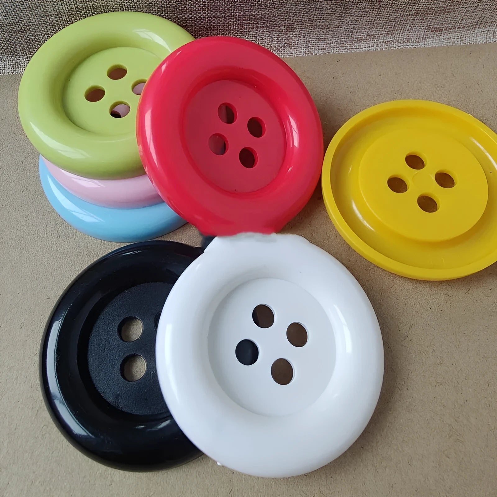 Oversized round edge plastic button with four holes in various colours and diameter sizes