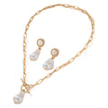 Gold-coloured baroque pearl pendant necklace and earring set on a dark background.