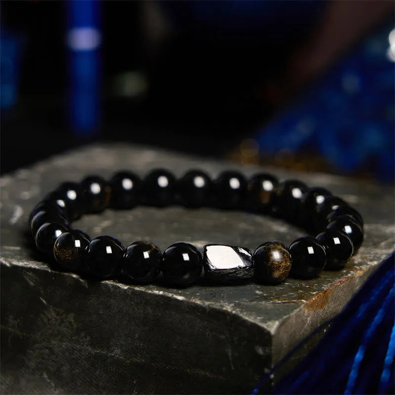 Natural obsidian single ring bracelet with constellation modelling on a wrist.